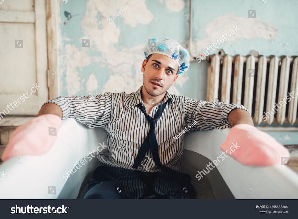 weird-stock-photo-naive-businessman-in-swimming-hat-lies-in-bathtub.